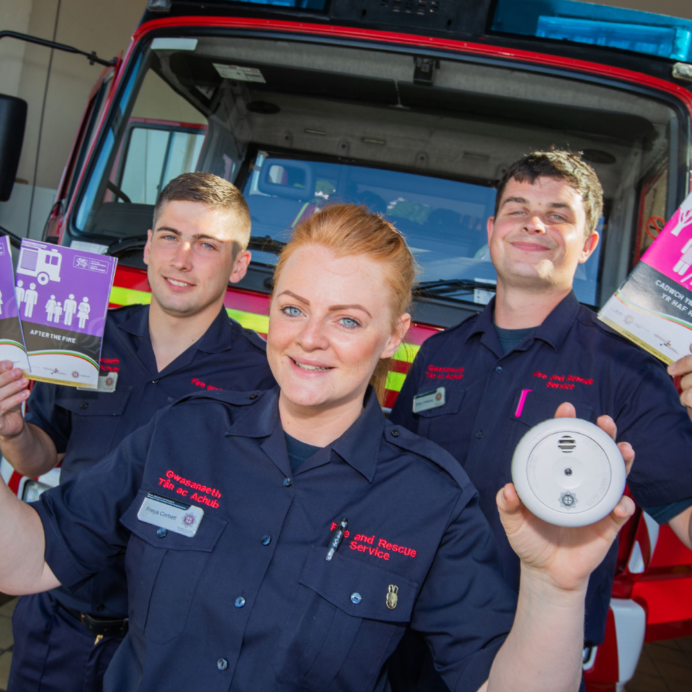 Apprentices holding smoke alarms and leaflets